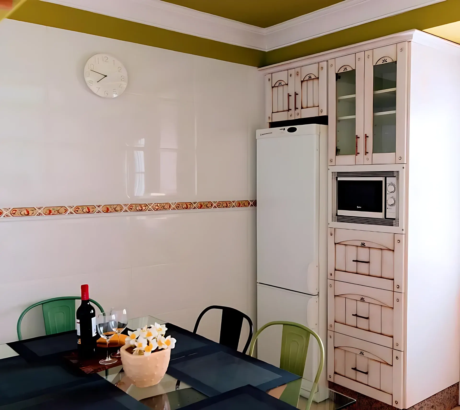 Zona de cocina con nevera, microondas y mesa preparada